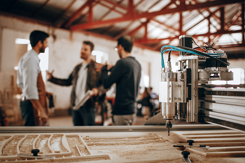 three men talking in front of a printing machine